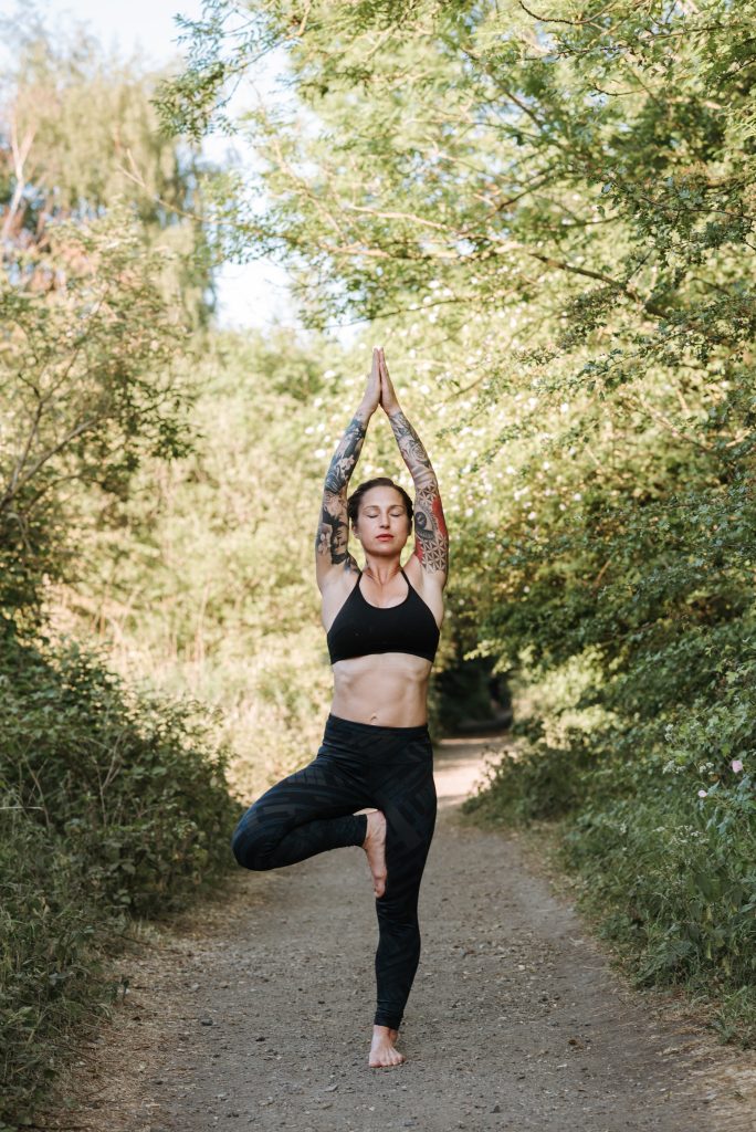 Kobieta w lesie ćwiczy jogę. Pozycja drzewa